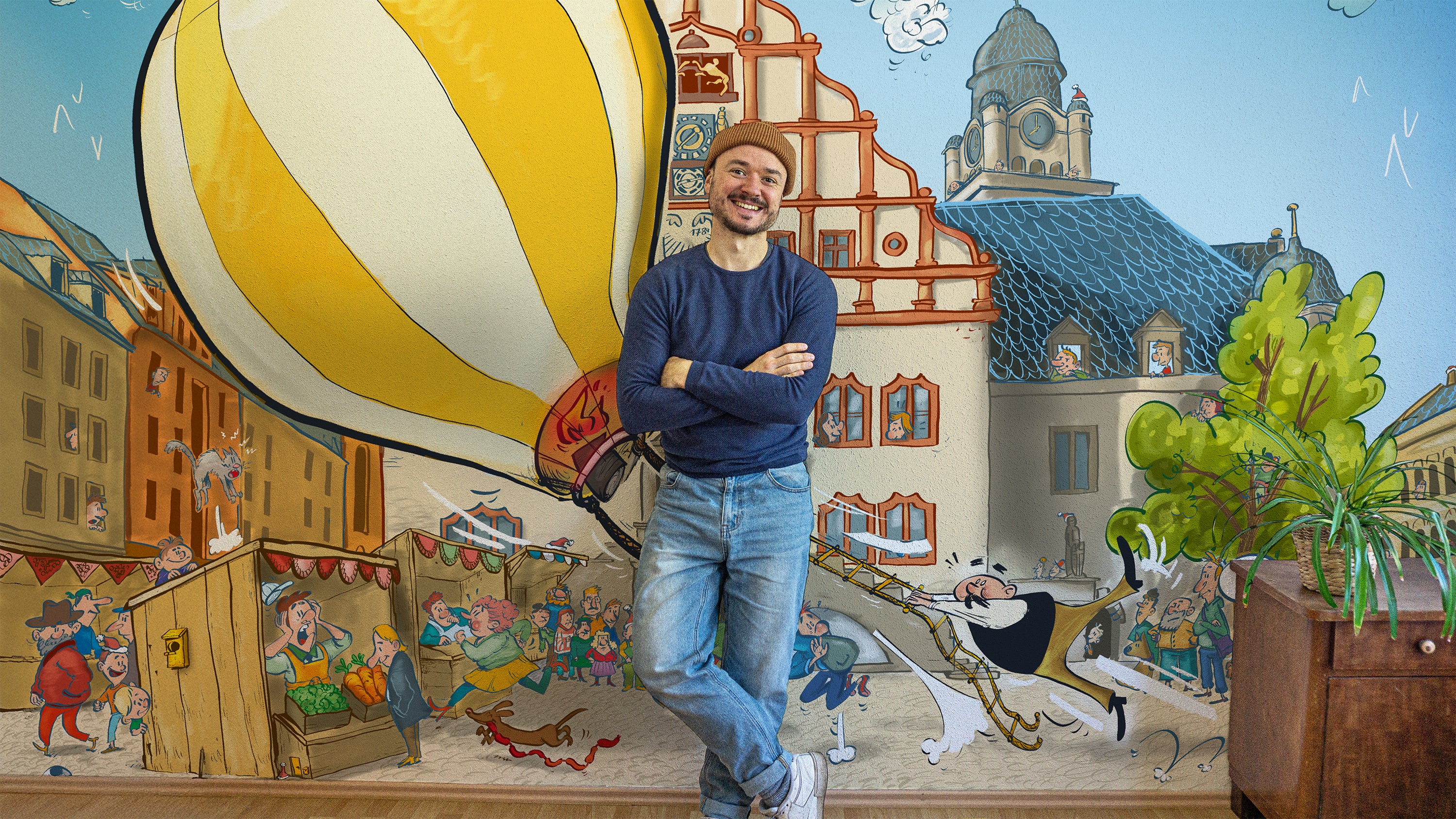 Ein junger Mann lehnt lächelnd an einer bunten Wand. 